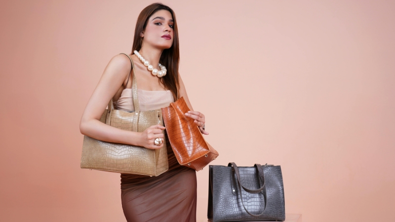 Žena pozira sa nekoliko elegantnih kožnih torbi različitih boja i veličina